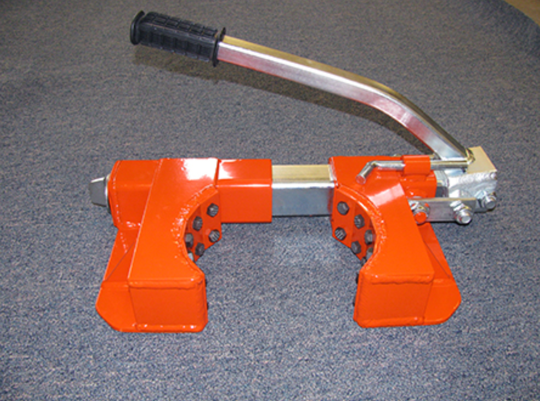 An orange tool with a black handle sits on a concrete surface