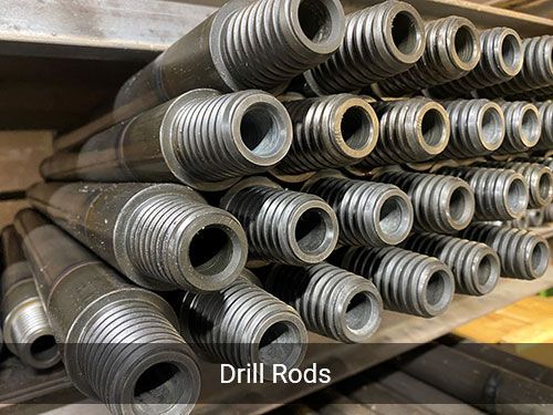 A bunch of drill rods are stacked on top of each other on a shelf.