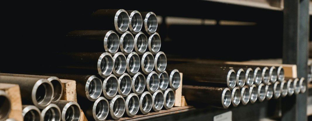 A bunch of drill rods are stacked on top of each other on a shelf.