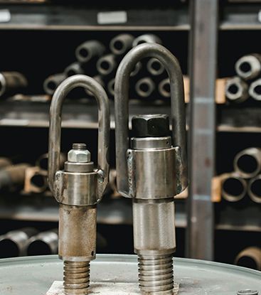 Two metal hooks are sitting on top of a metal barrel