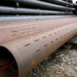 A bunch of rusty pipes are stacked on top of each other on the ground.