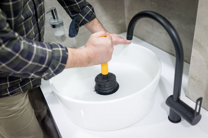 Plumber's hand using plunger — Delta, CO — On a Budget Rooter