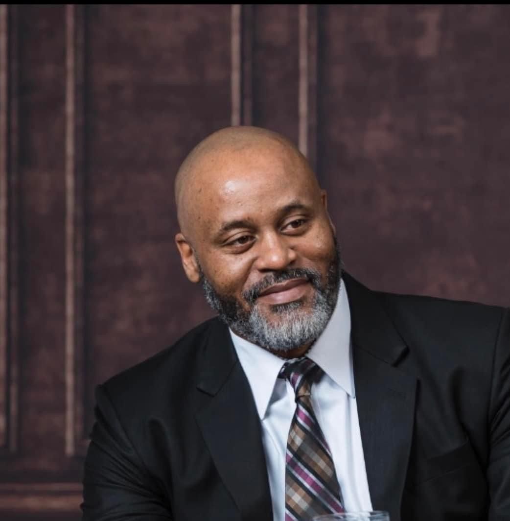 A bald man with a beard wearing a suit and tie