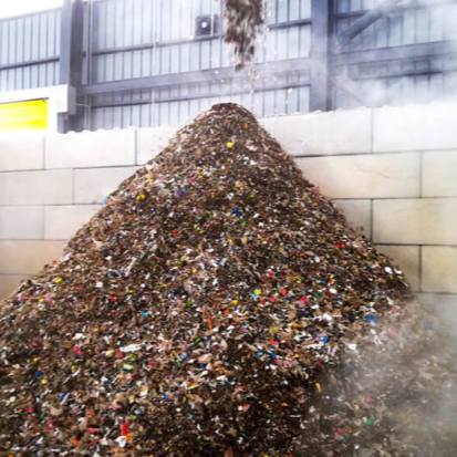 Gran montón de chatarra de metal mixto en un almacén industrial, con vapor o humo a su alrededor.