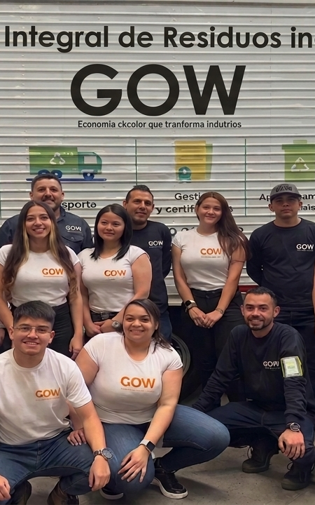 Grupo de personas posando frente a un cartel y una pancarta de GOW en un evento o taller.