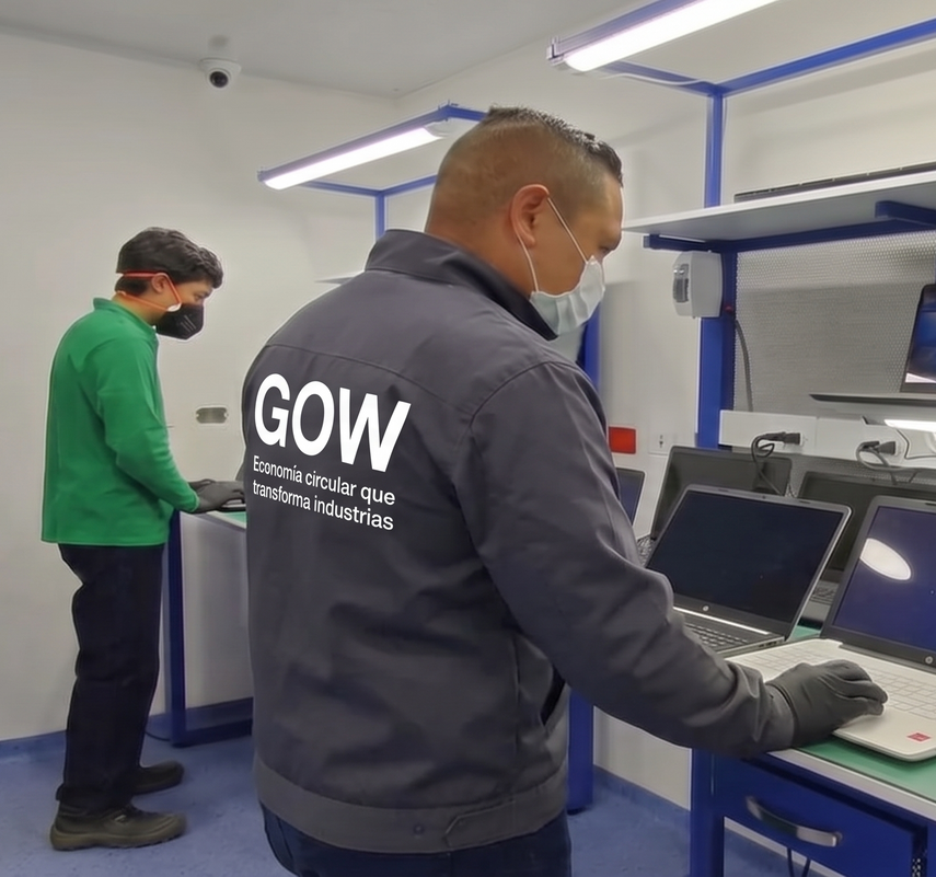 Dos trabajadores en un laboratorio bien iluminado utilizando ordenadores portátiles y equipos en una mesa de trabajo.