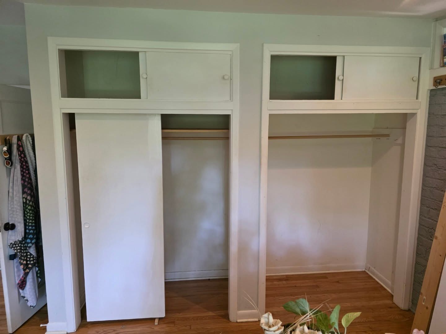 White built-in closet with open cabinets and hanging rods in a room, seen from the front.