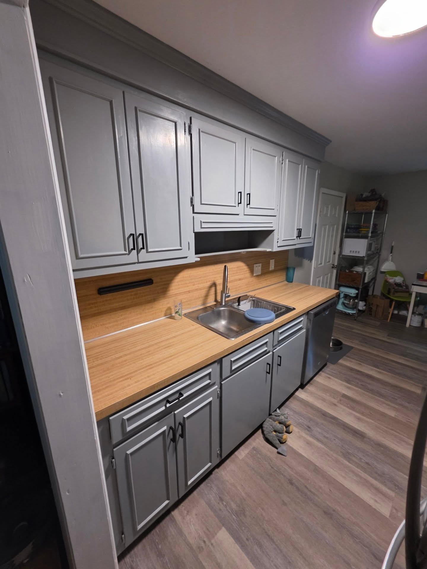 Small kitchen with gray cabinets, wood countertops, sink, and hardwood-style flooring.