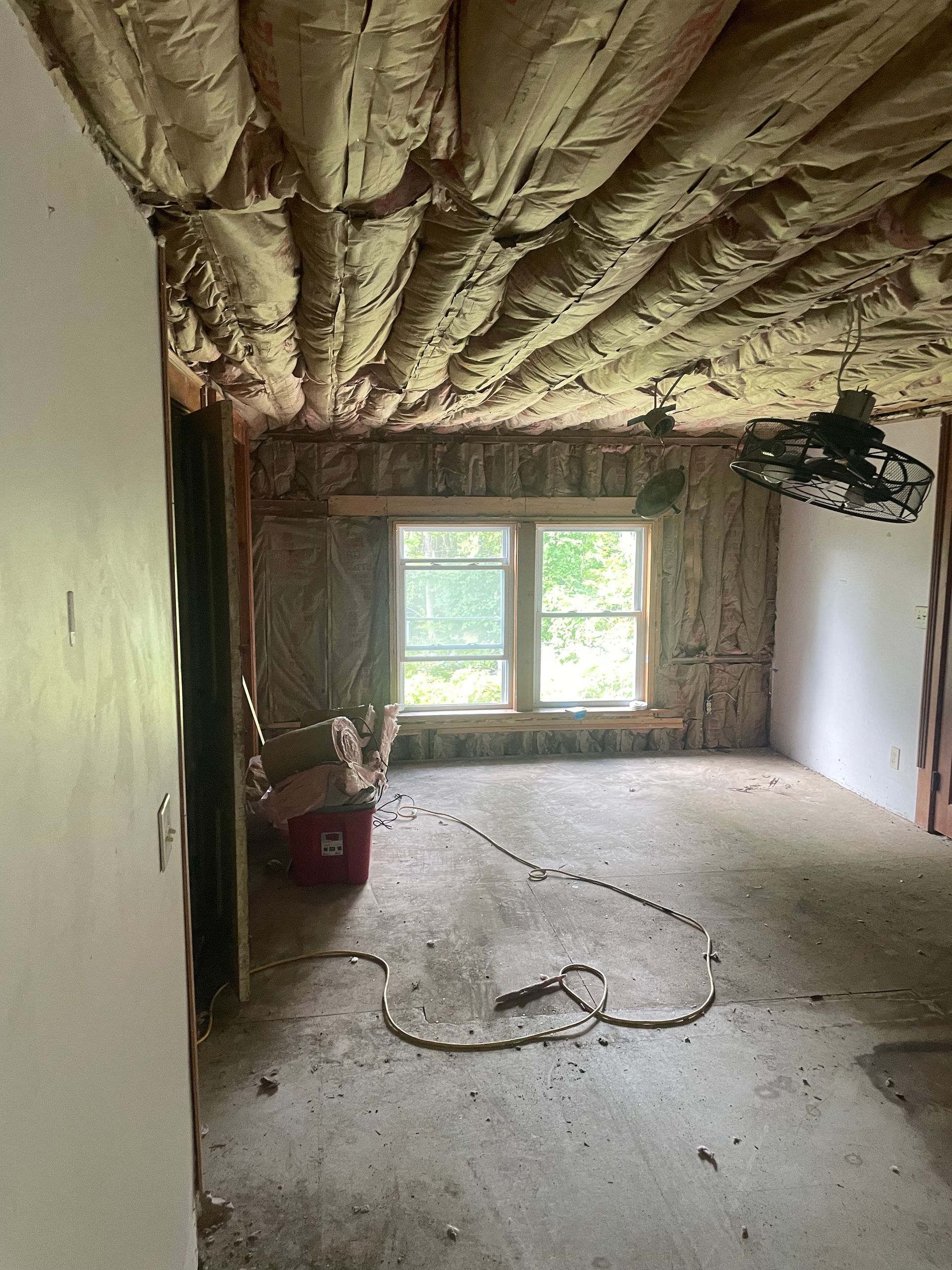 A room with a lot of insulation on the ceiling and a fan hanging from the ceiling.