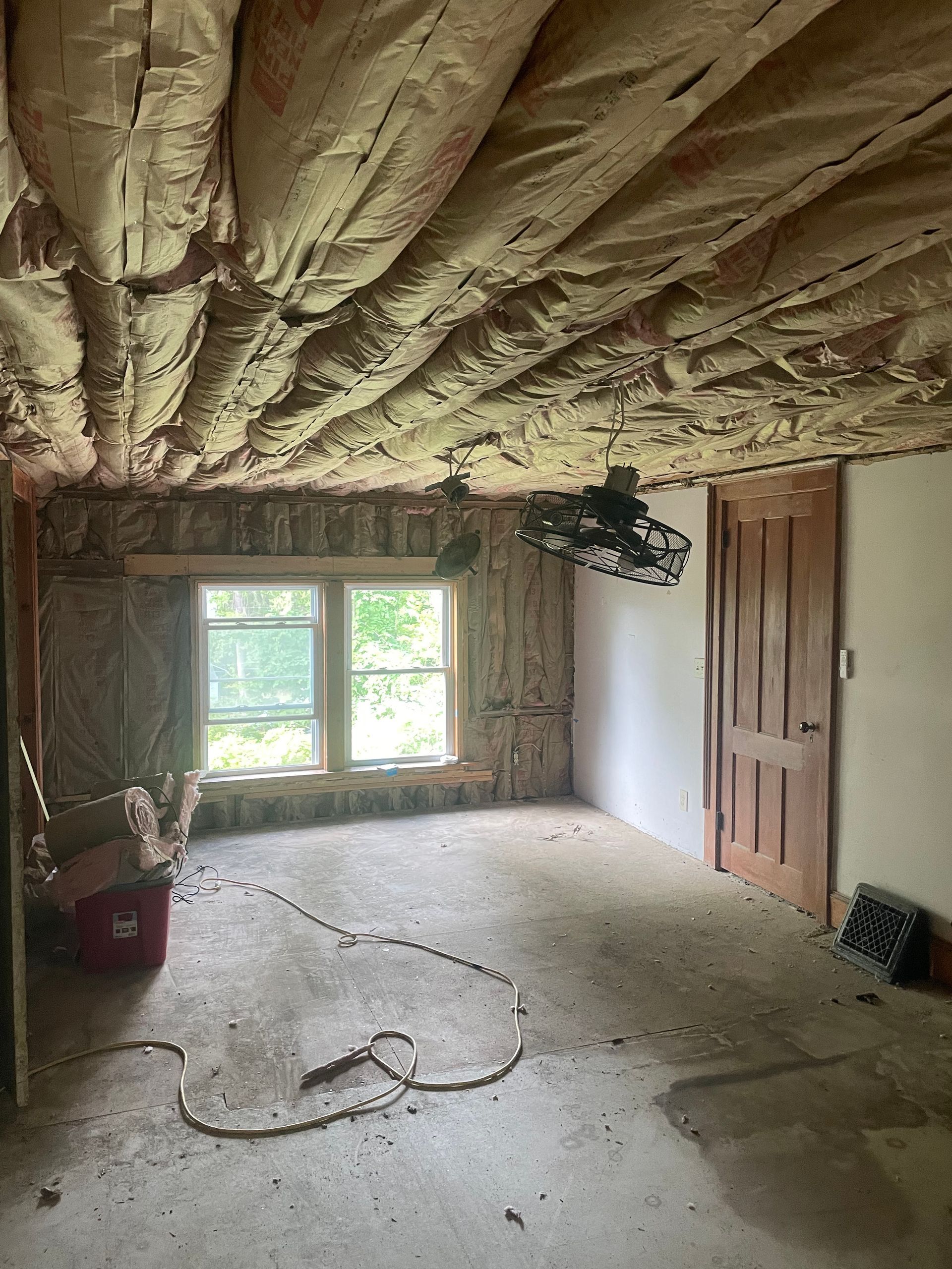 An empty room with a ceiling fan and a window.