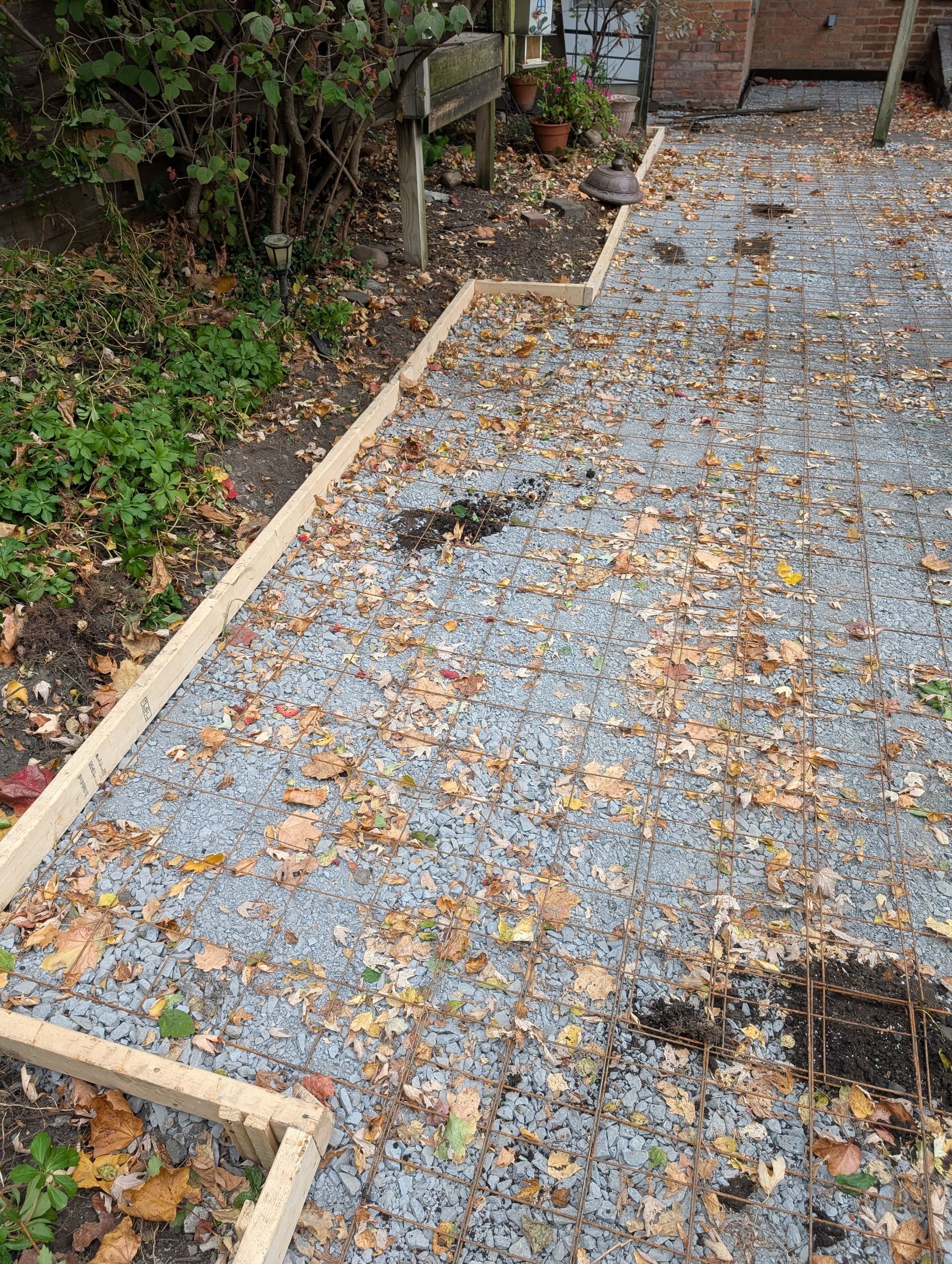 A gravel path with a wooden border and leaves on the ground.