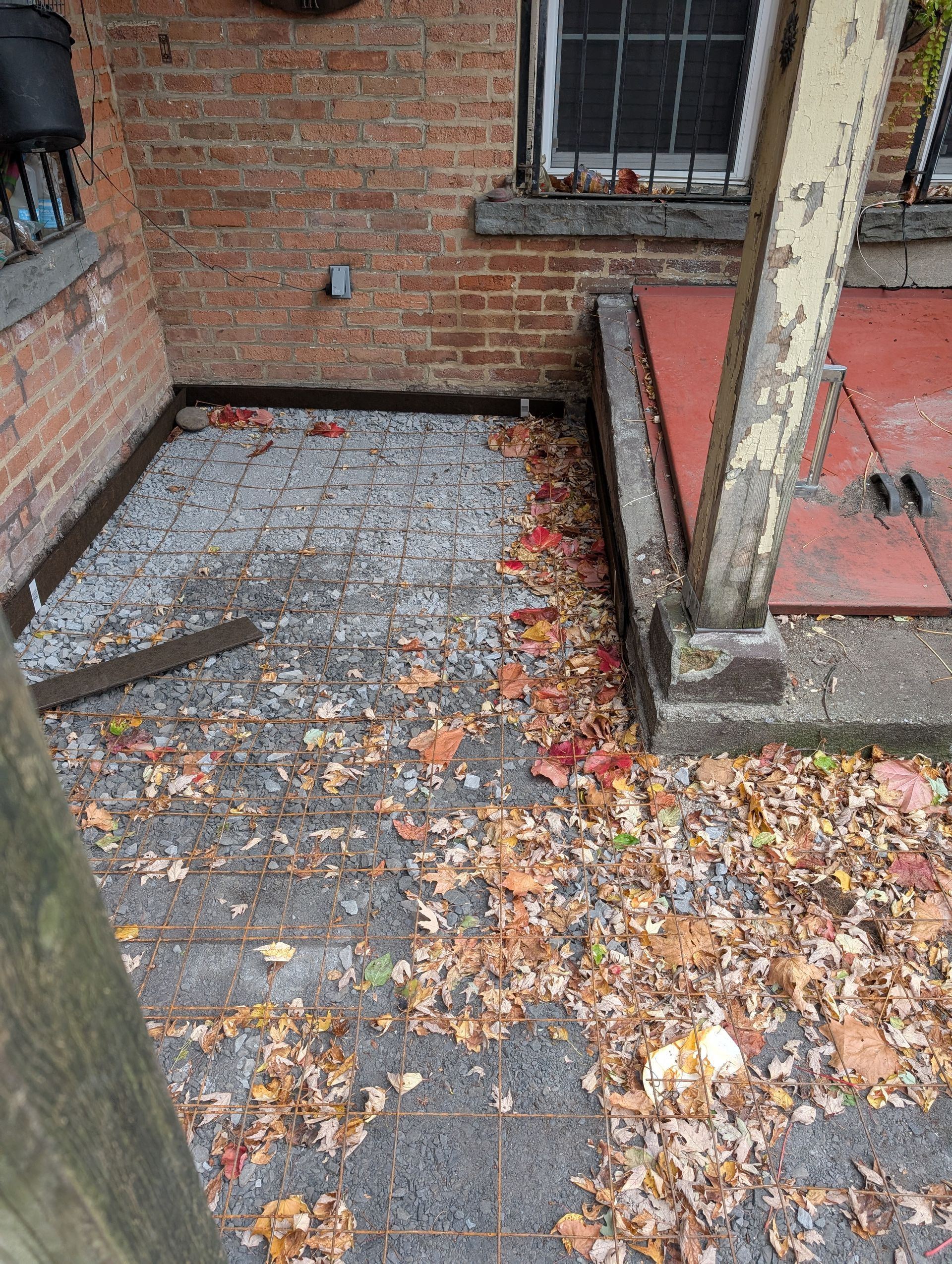 A brick building with a porch and a lot of leaves on the ground.