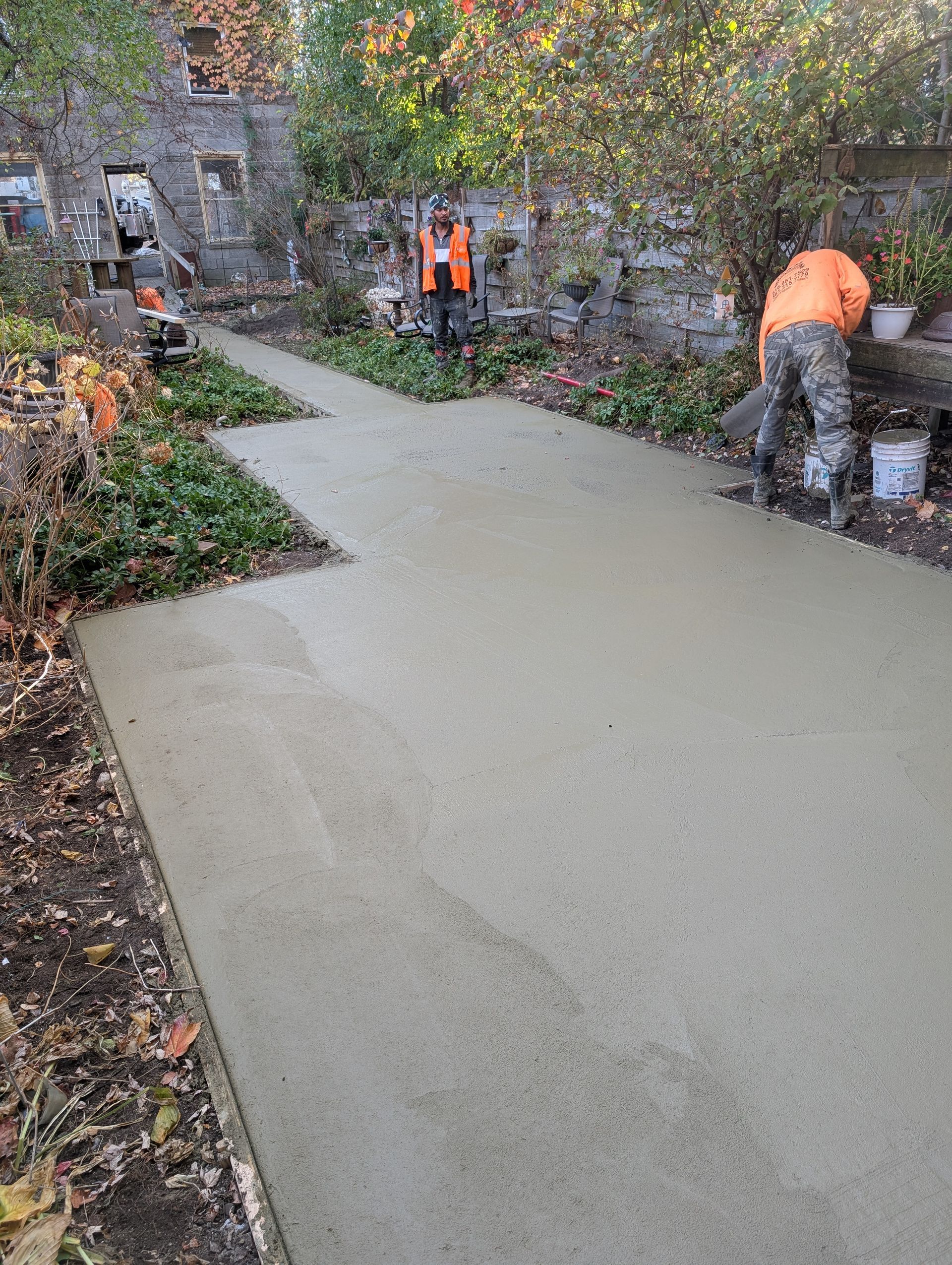 A group of men are working on a concrete driveway.