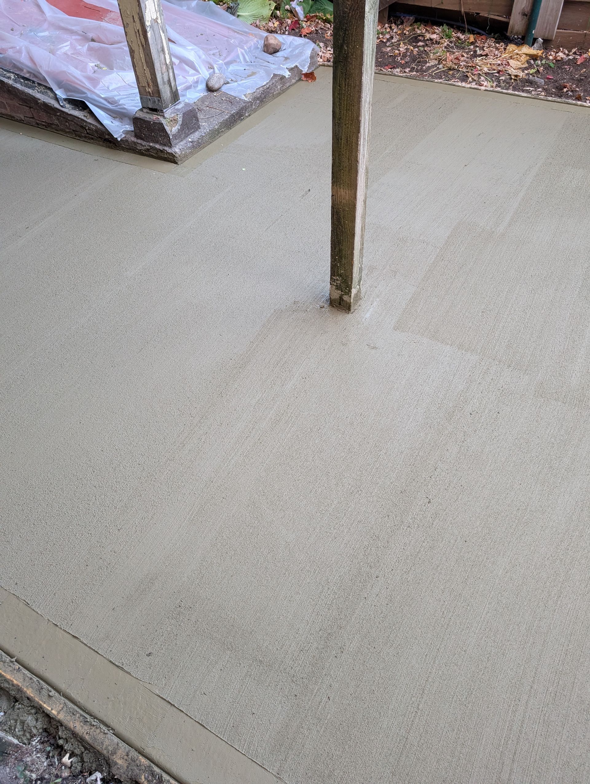 A close up of a concrete floor with a wooden post in the background.