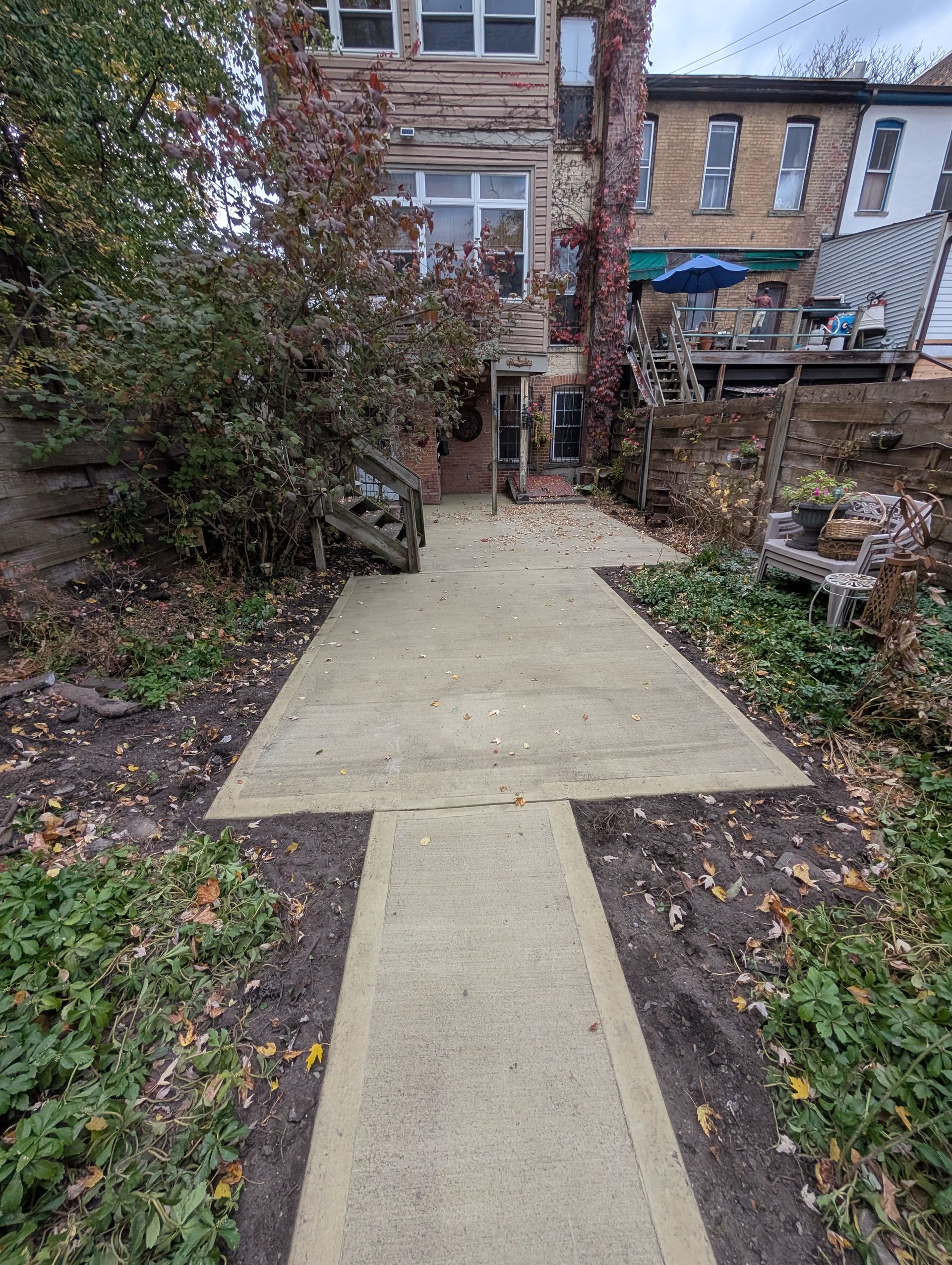 A concrete walkway leading to a house in a backyard.
