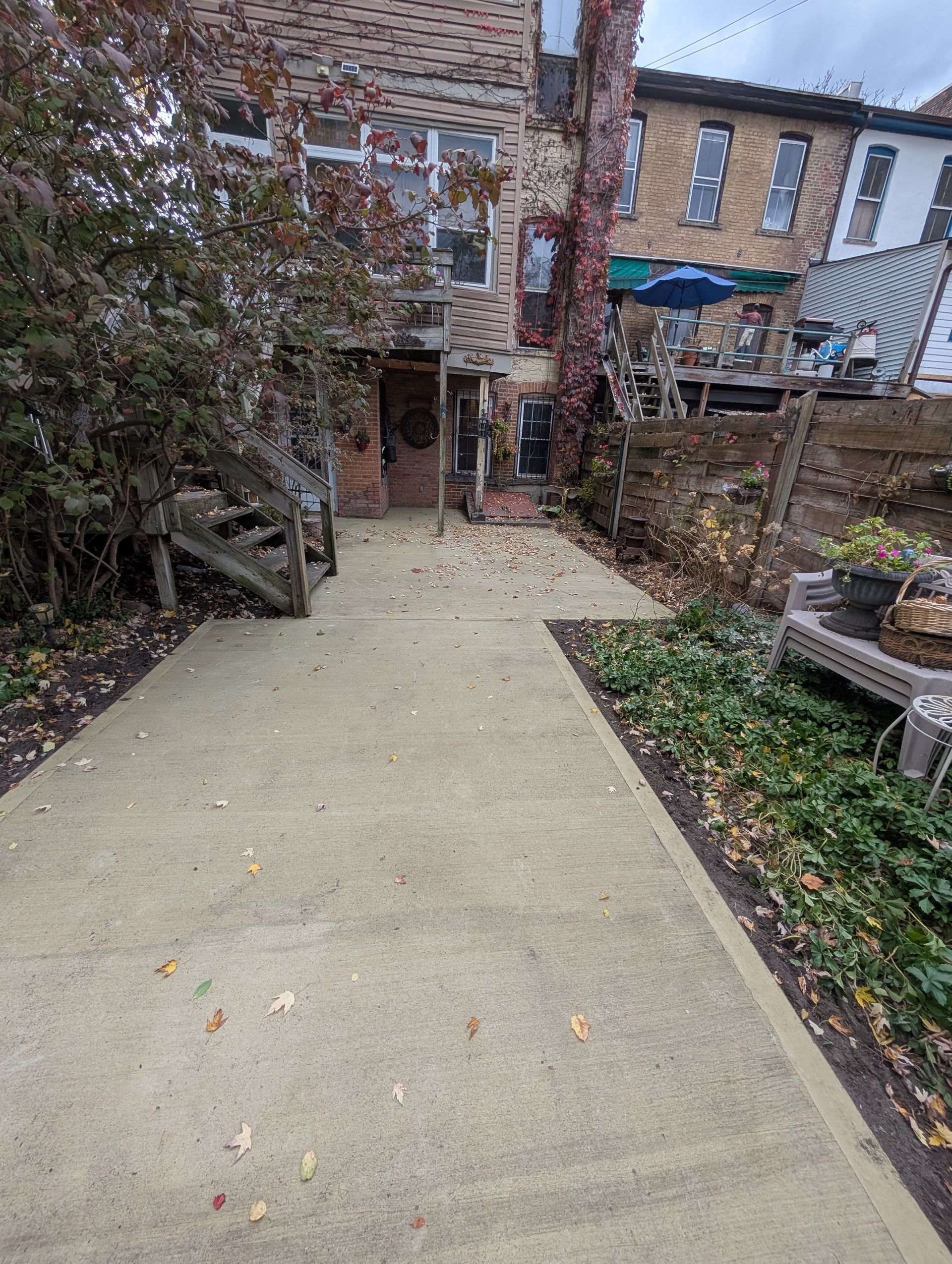 A concrete walkway leading to a house in the backyard.