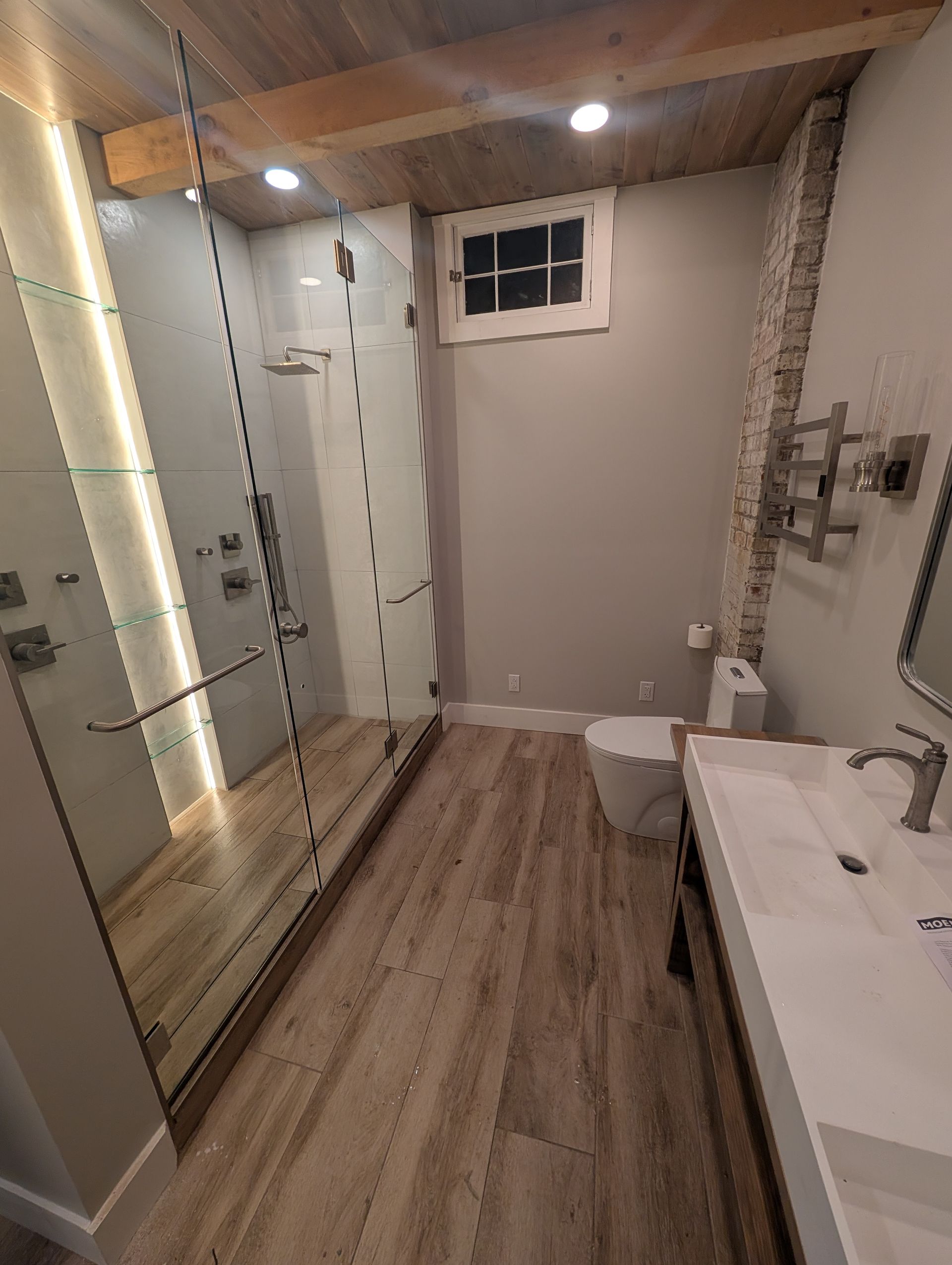 A bathroom with a sink , toilet , shower and mirror.
