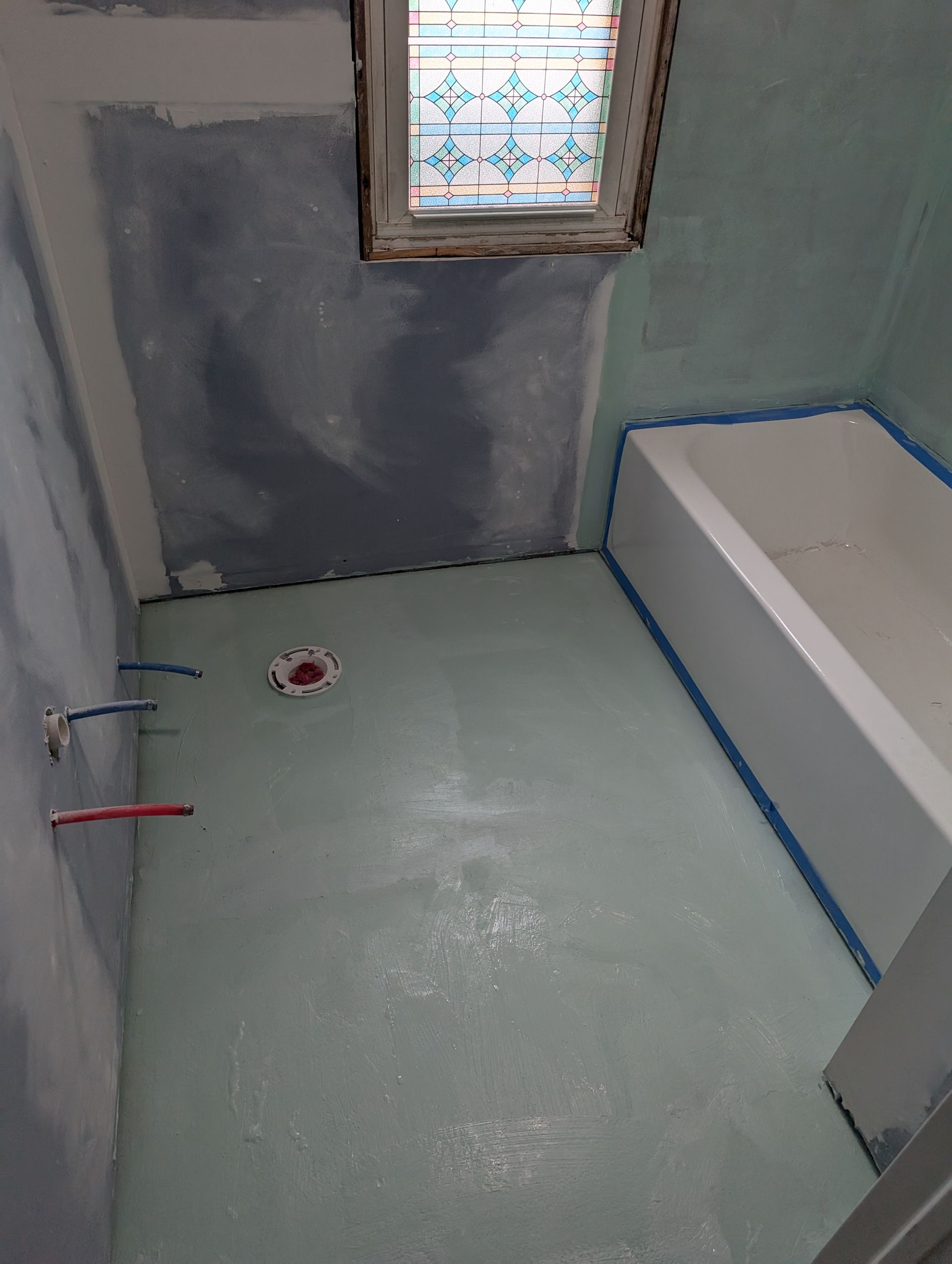 A bathroom under construction with a bathtub and a window.