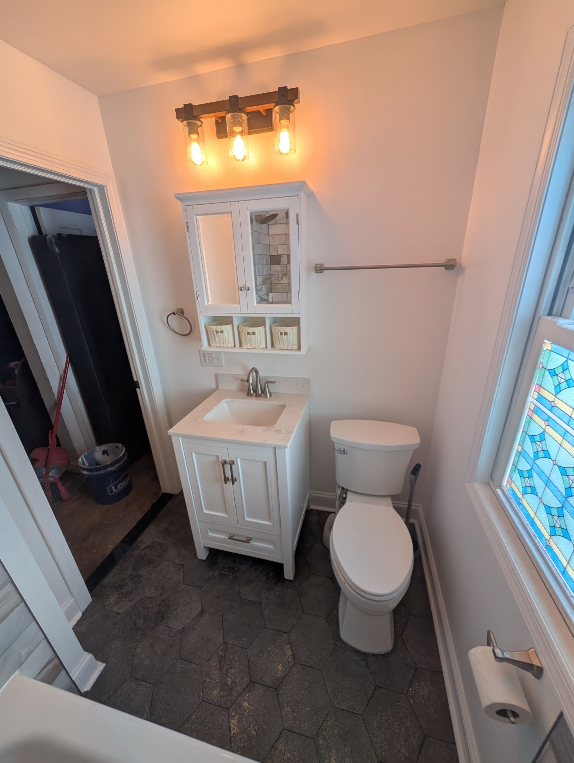 A bathroom with a toilet , sink and mirror.