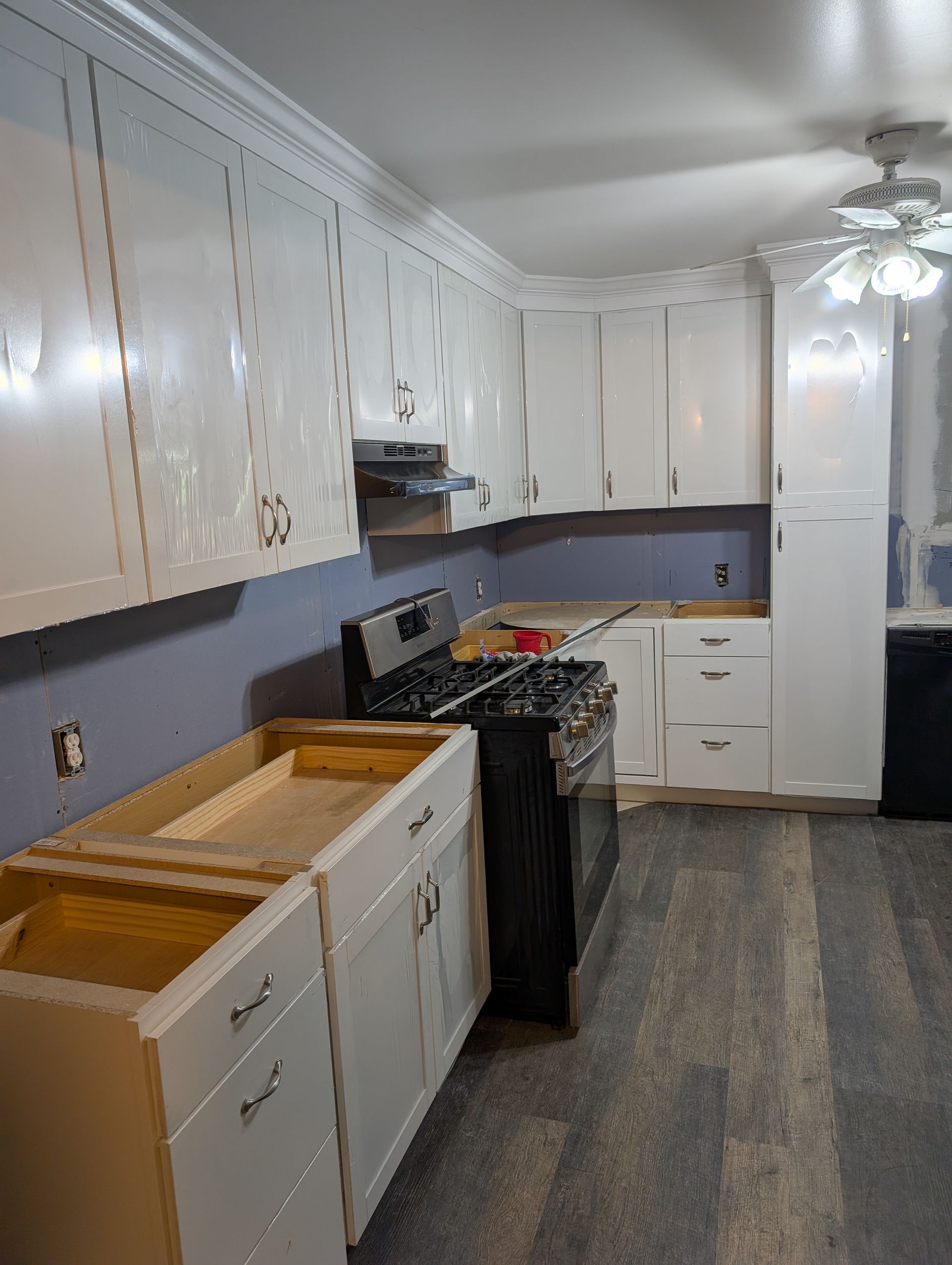 A kitchen with white cabinets , a stove , and a sink.