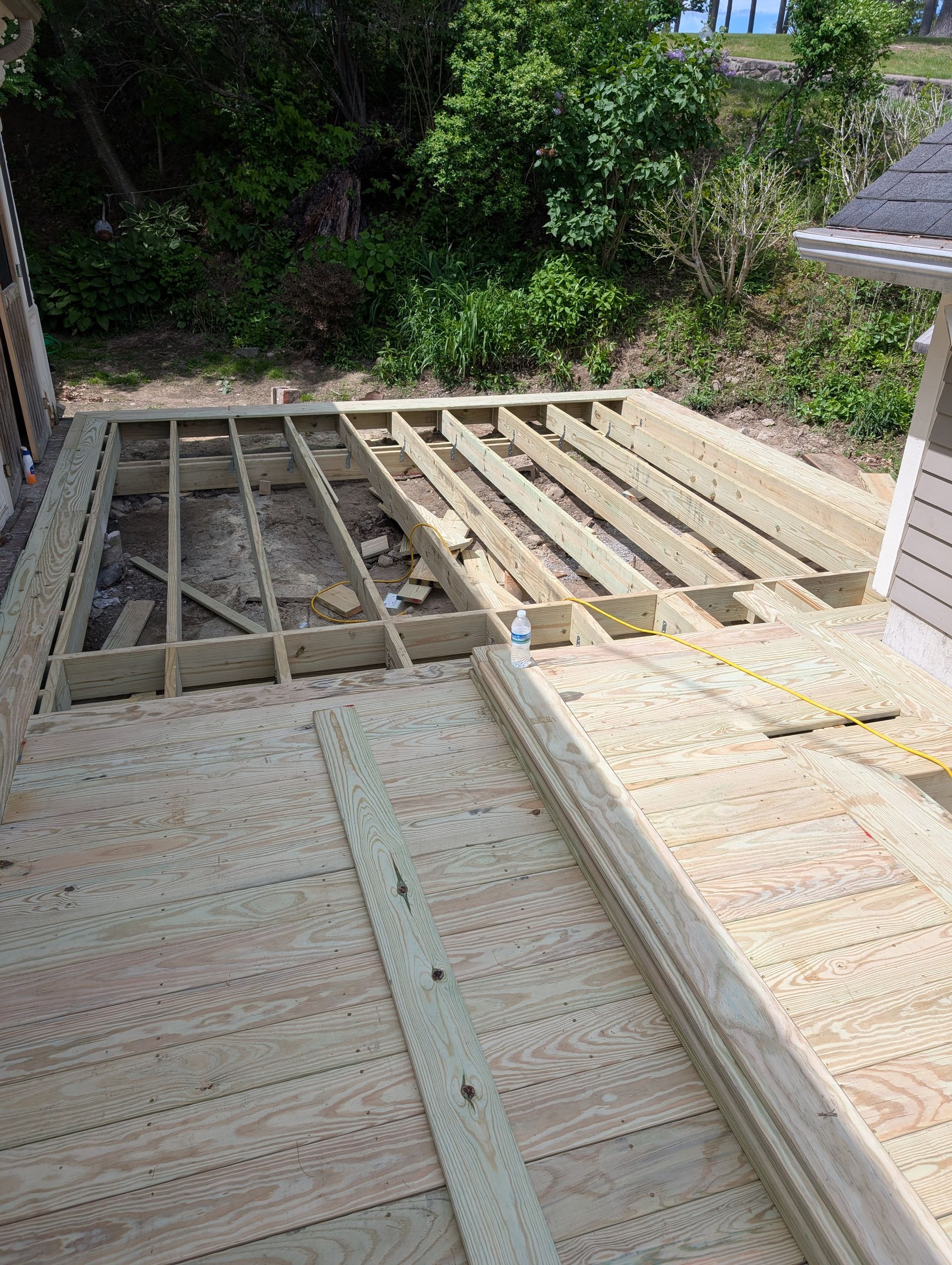 A wooden deck is being built in the backyard of a house.