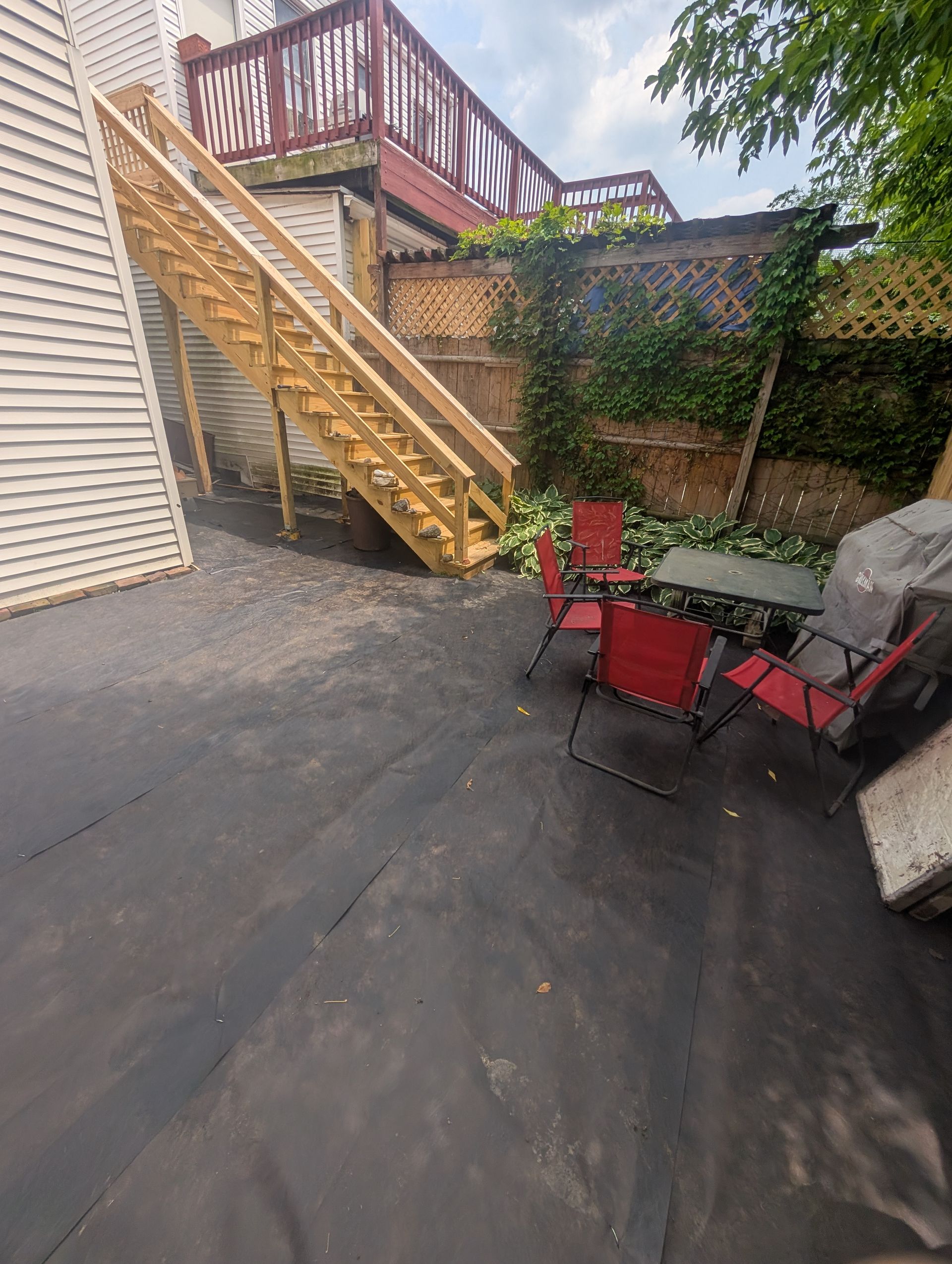 A patio with a table and chairs and stairs leading up to a deck.