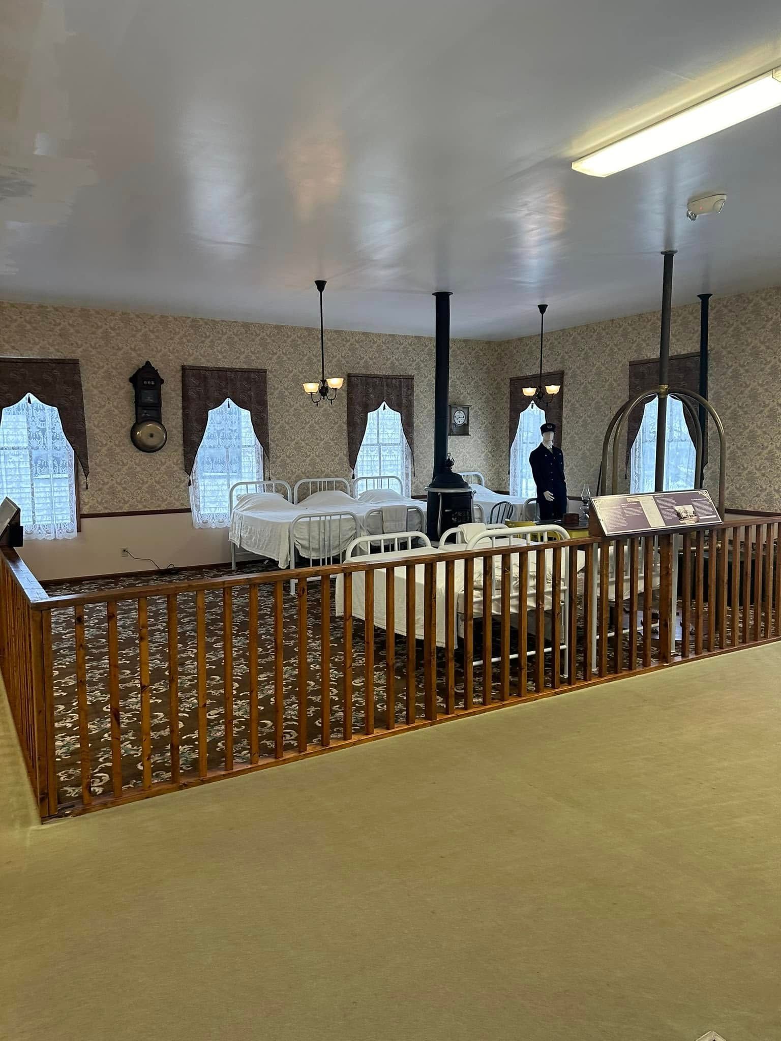 Indoor banquet hall with arched windows, white table settings, and a wooden railing in the foreground