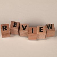 Wooden blocks spelling “REVIEW” on a beige surface.