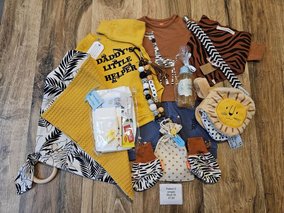 Kleedjes voor peuters uitgestald op een houten vloer, waaronder gele, bruine, zebraprint en leeuwenoutfits.