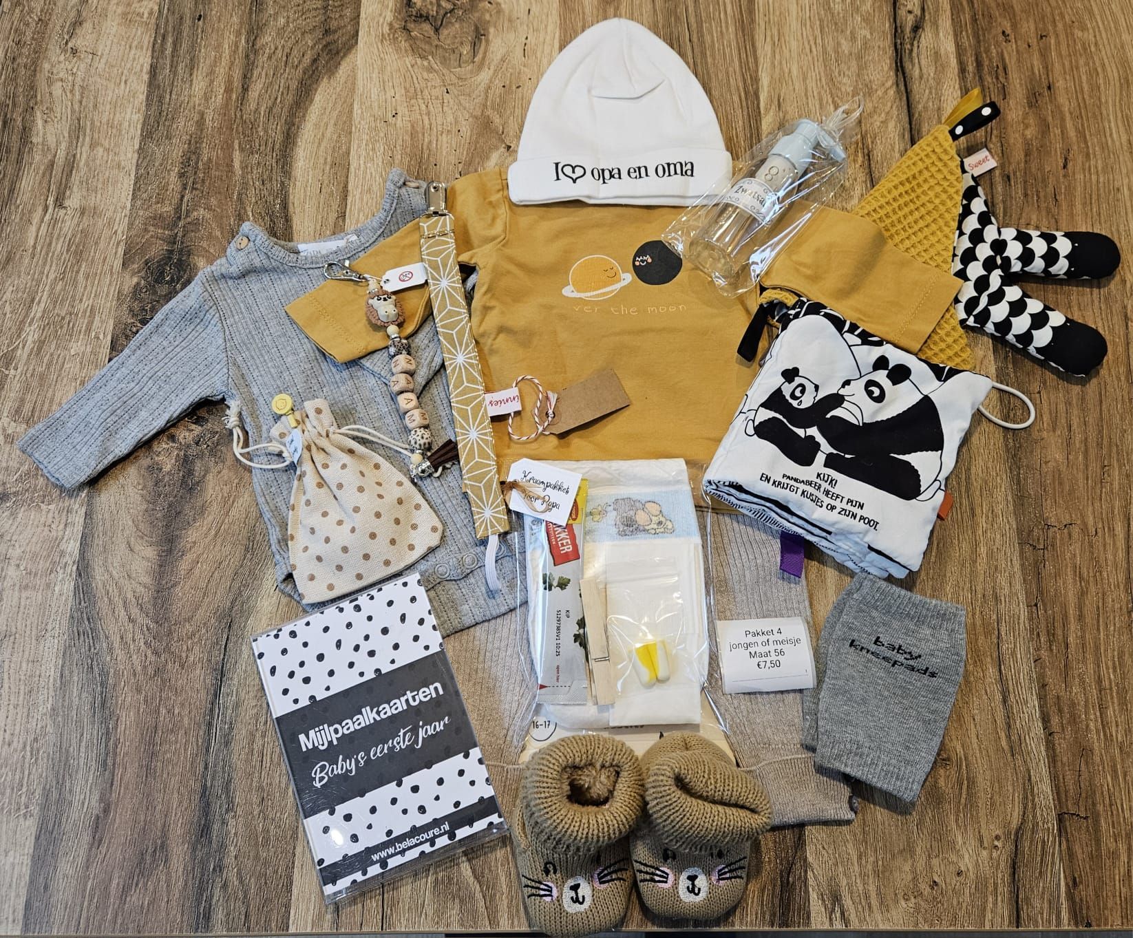 Een bundel kinderkleding en accessoires, uitgestald op een houten vloer, bestaat voornamelijk uit gele, grijze en zwarte stukken.