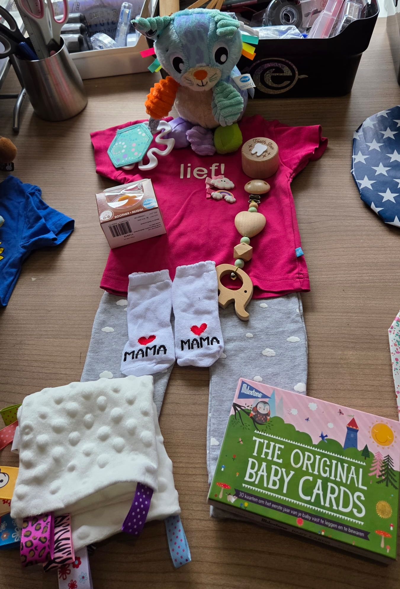 Babycadeau-display met roze outfit, knuffelolifant, bijtring, sokjes, dekentje en doos met
