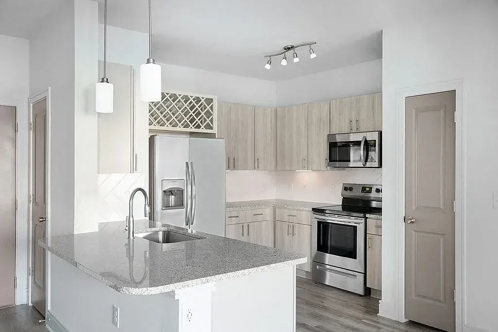 Bright white kitchen with granite island, stainless appliances, and pendant lights at Azure Carnes Crossing in Summerville