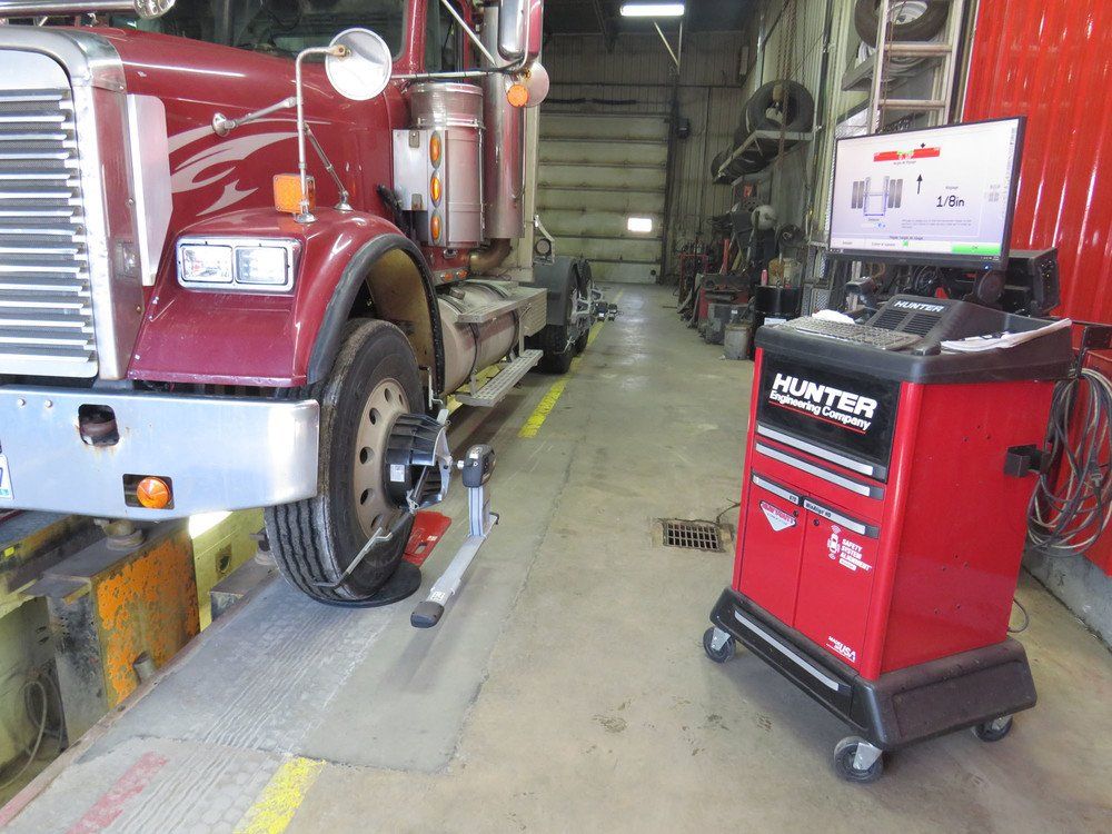 Un pneu rouge de semi-remorque est aligné dans un garage par une machine Hunter.