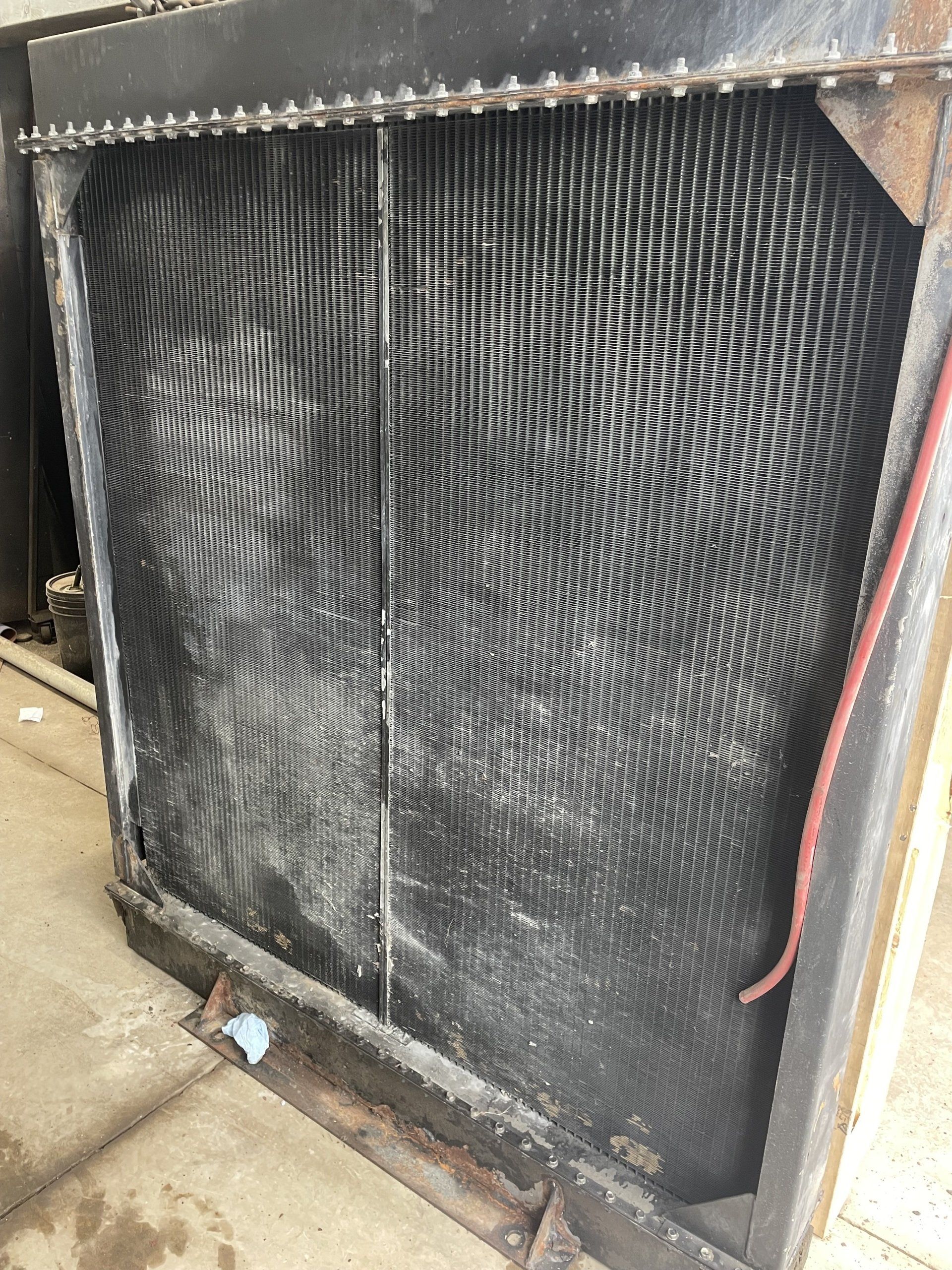 Grand radiateur industriel avec un noyau en maille noire dans un cadre en métal.