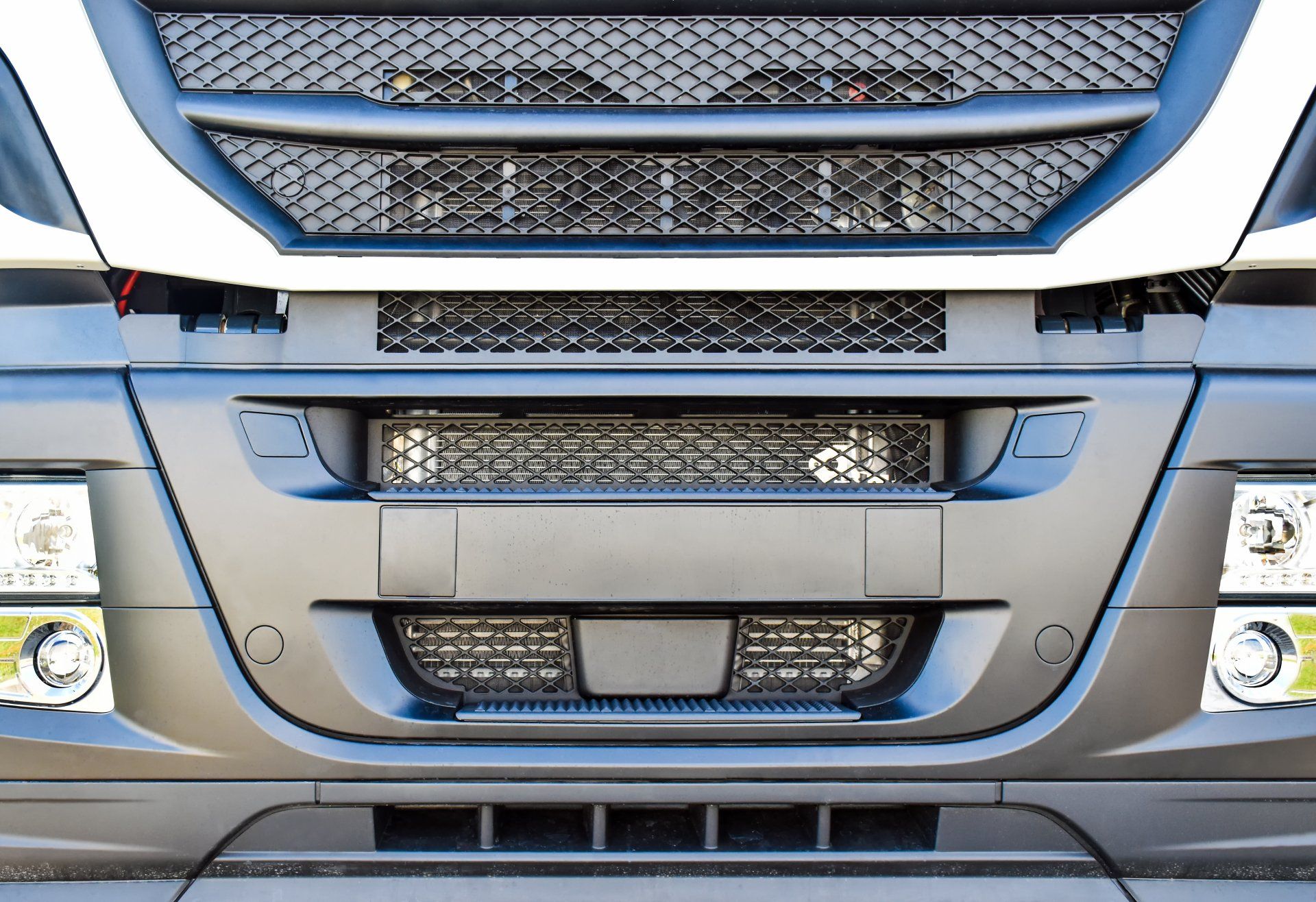 Gros plan de l'avant d'un camion gris, montrant la calandre, le pare-chocs, les phares et le réseau de capteurs.