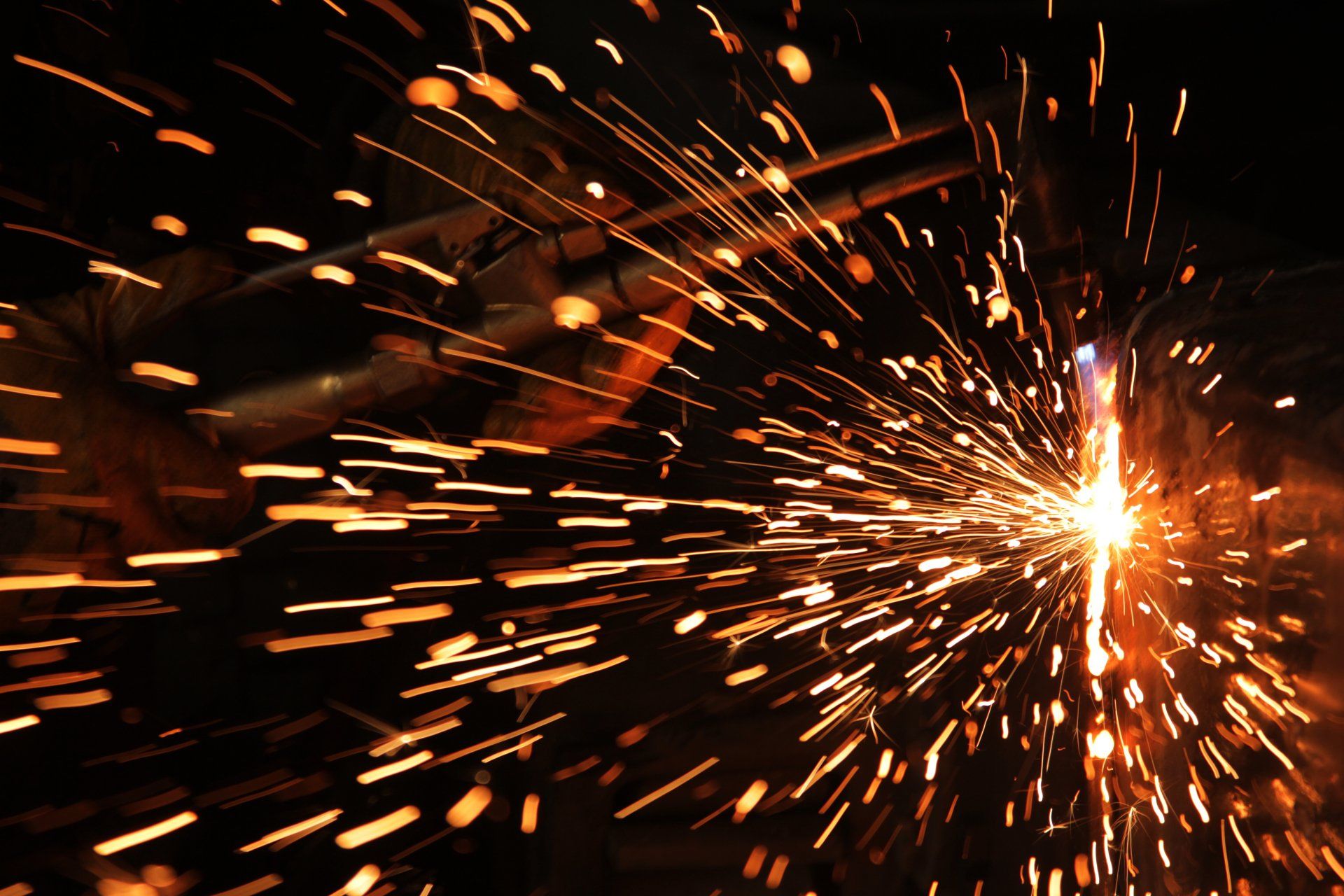Soudeur au travail, des étincelles brillantes volent dans l'obscurité.