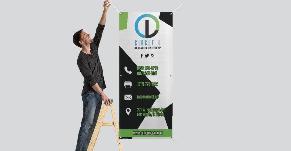 A man is standing on a ladder hanging a banner on a wall.