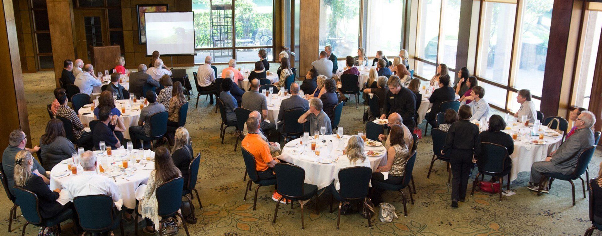 A large group of people are sitting at tables in a large room.