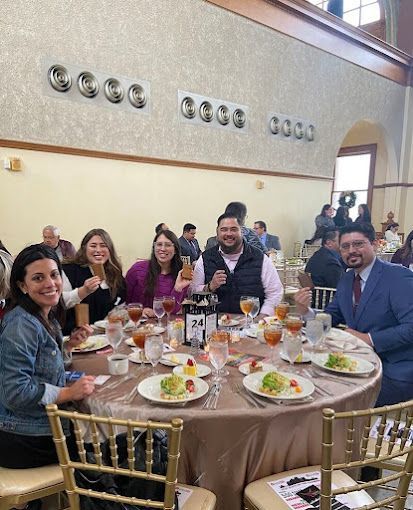 A group of people are sitting at a table with plates of food and drinks.