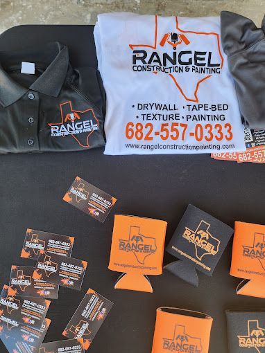 A table topped with shirts and business cards for rangel construction and painting