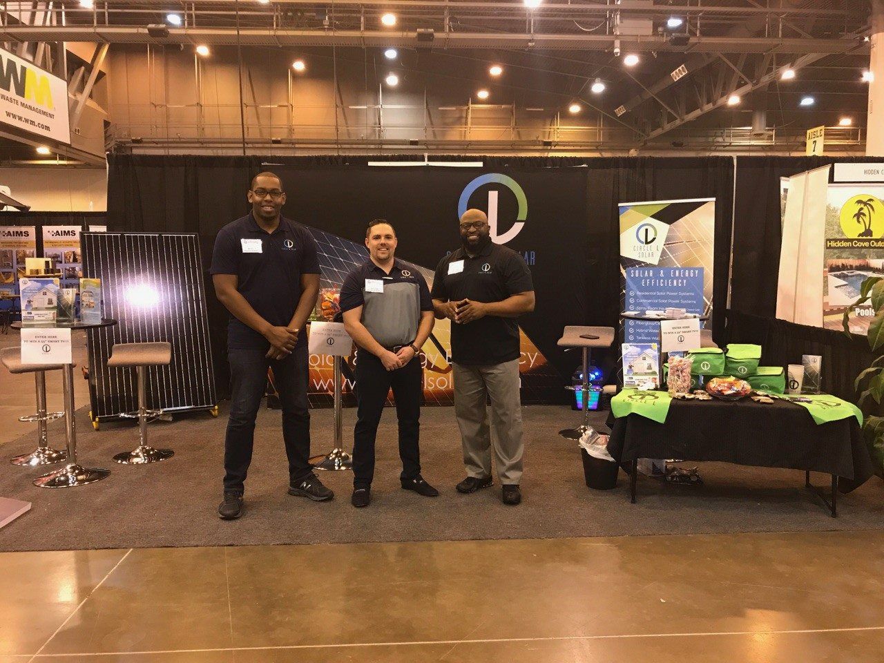 Three men are standing in front of a booth at a convention.