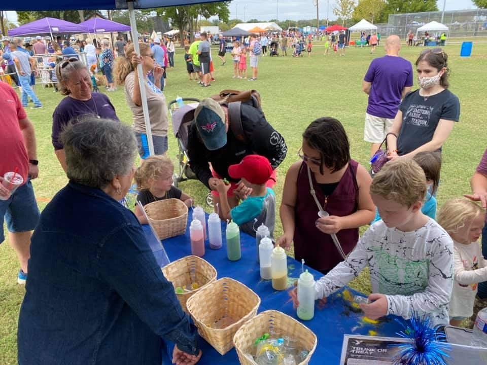 A group of people are standing around a table in a park.