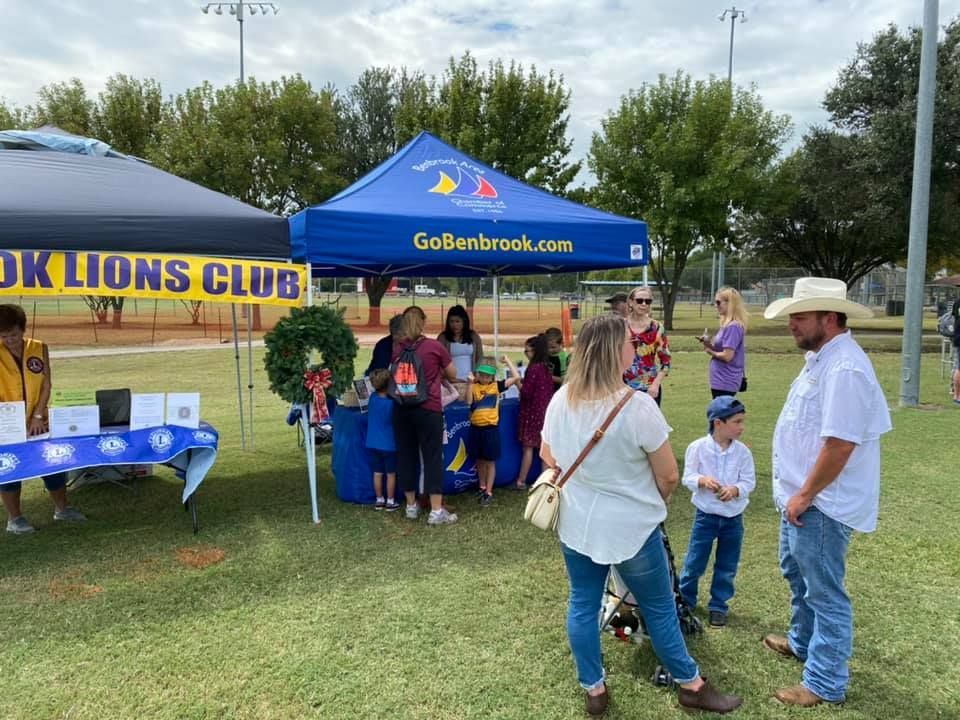 A group of people are standing under a tent in a park.