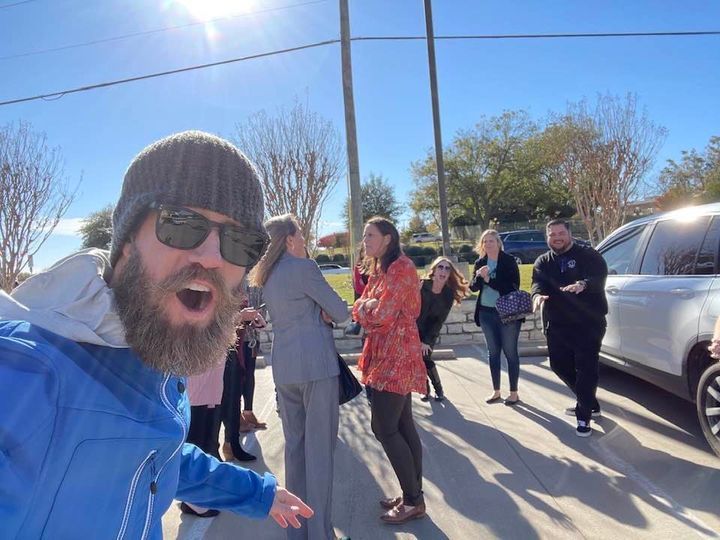 A man with a beard is standing in front of a group of people.