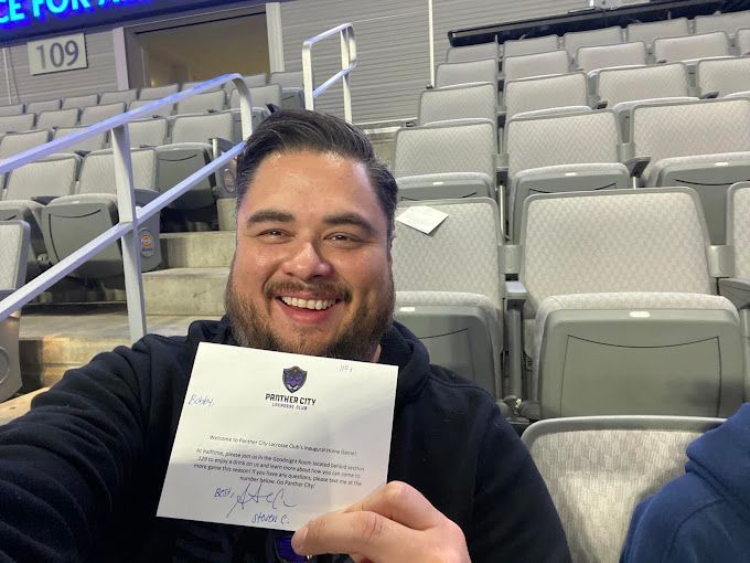 A man is sitting in an empty stadium holding a ticket.