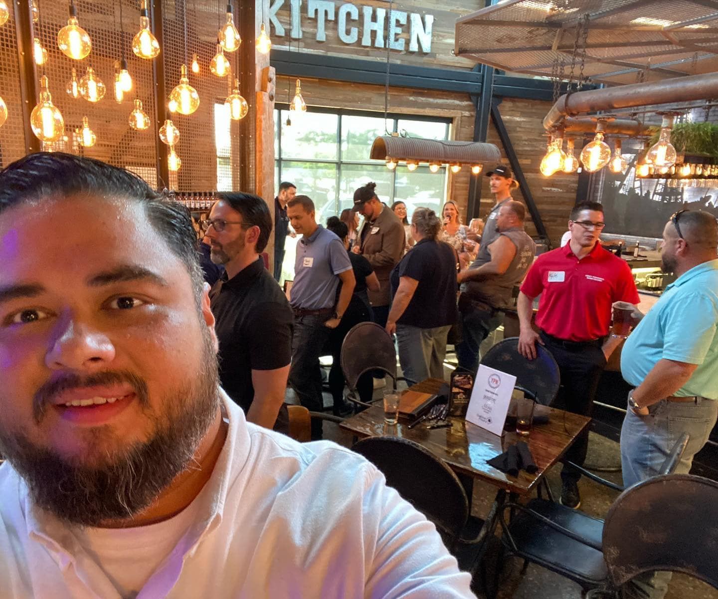 A man with a beard is taking a selfie in front of a kitchen sign.