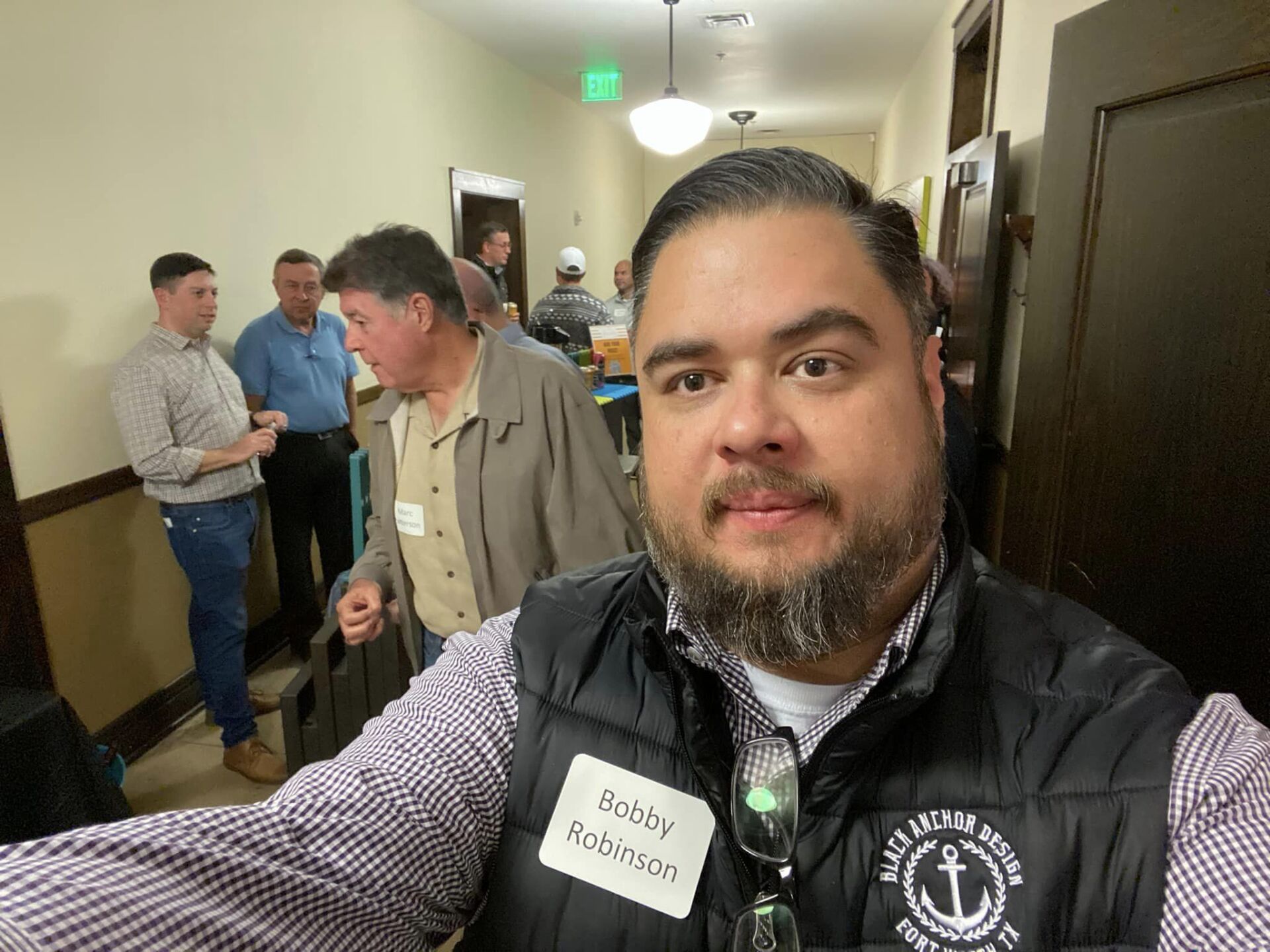 A man with a beard is taking a selfie in a hallway.