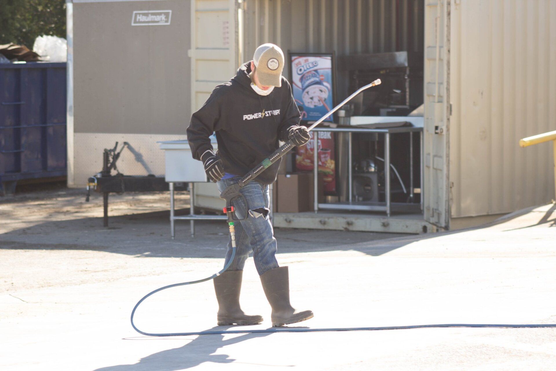 A man is standing in front of a building holding a hose.