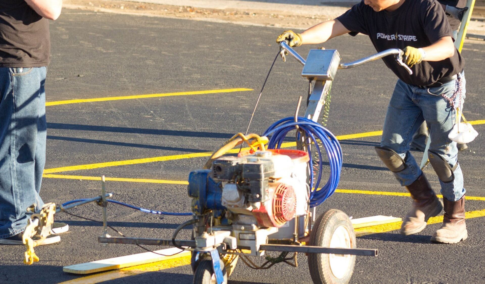A man is using a machine to paint yellow lines on the road