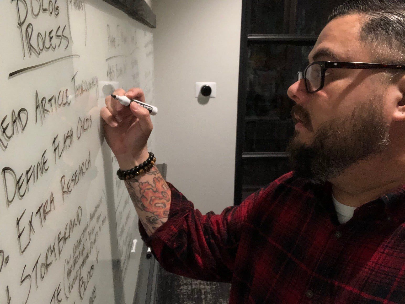 A man is writing on a white board with a marker